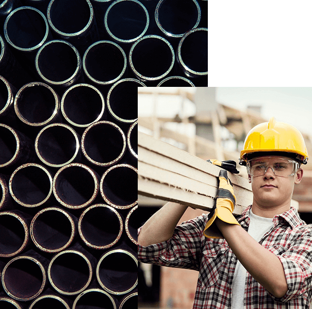 A man holding a piece of wood in front of a bunch of pipes.