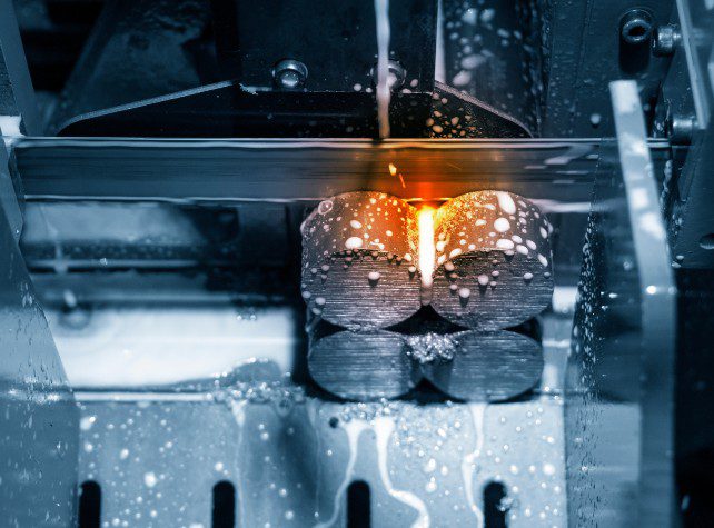 A machine is making metal objects with sparks flying.